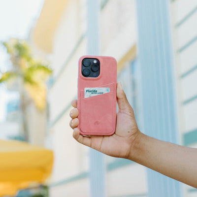 A hand holding a pink Minimalist Portfolio Case with a Florida ID card visible in the pocket.