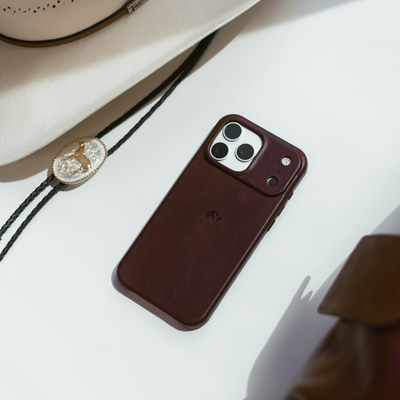 Slim full-grain leather iPhone case in bourbon brown with camera cutout and small embossed elephant logo