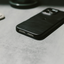 Slim black phone case on a gray tabletop, angled view showing back and bottom charging port cutout