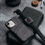A black minimalist portfolio case with card slots, placed on a textured surface alongside a smartwatch and earbuds.
