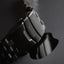 Black metal link Apple Watch strap, close-up of clasp engraved 'bullstrap'